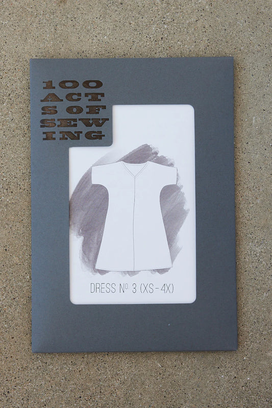 A paper sewing pattern for a caftan with a V-neck front and center seam, labeled as Dress No. 3 by 100 Acts of Sewing.