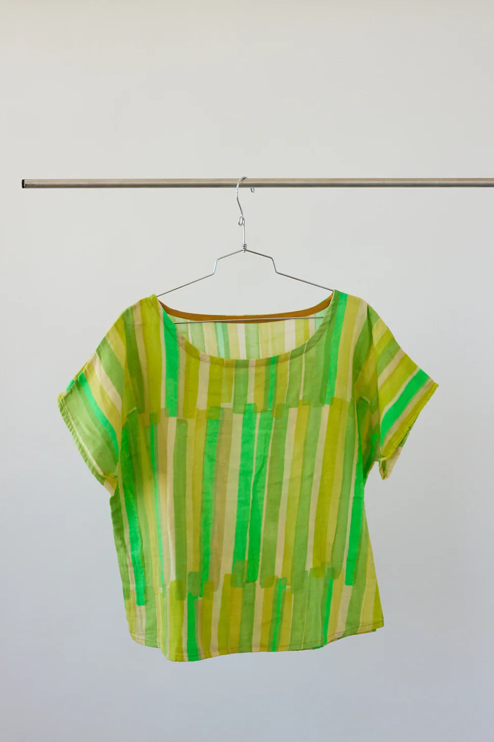 Green and yellow striped shirt on a hanger against a white background