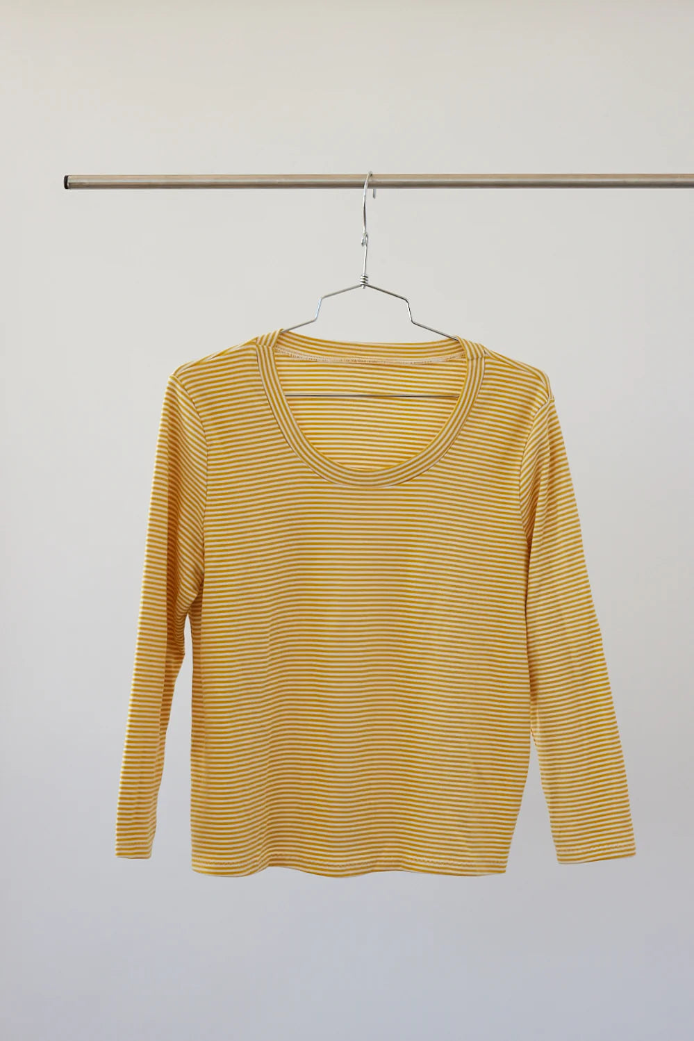 Yellow striped long-sleeve shirt on a hanger against a white background