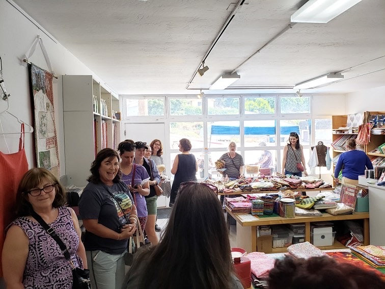 A large gathering of people buying fabric from QuiltnThings