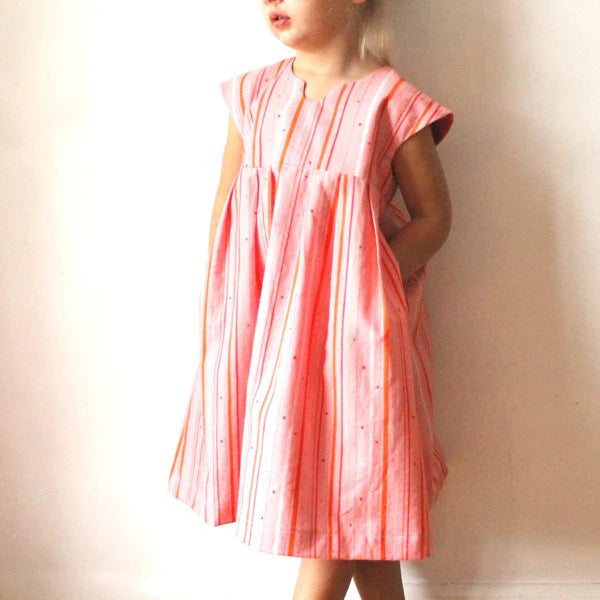 Child wearing a pink dress with a subtle pattern against a plain background