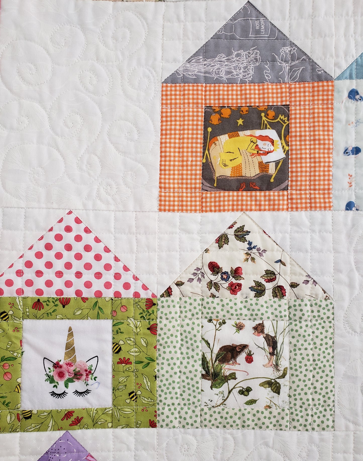 close up of house quilt showing a sleeping beauty, unicorn and mouse
