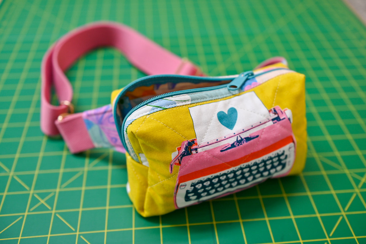 Small fabric pouch with a pink strap on a green cutting mat