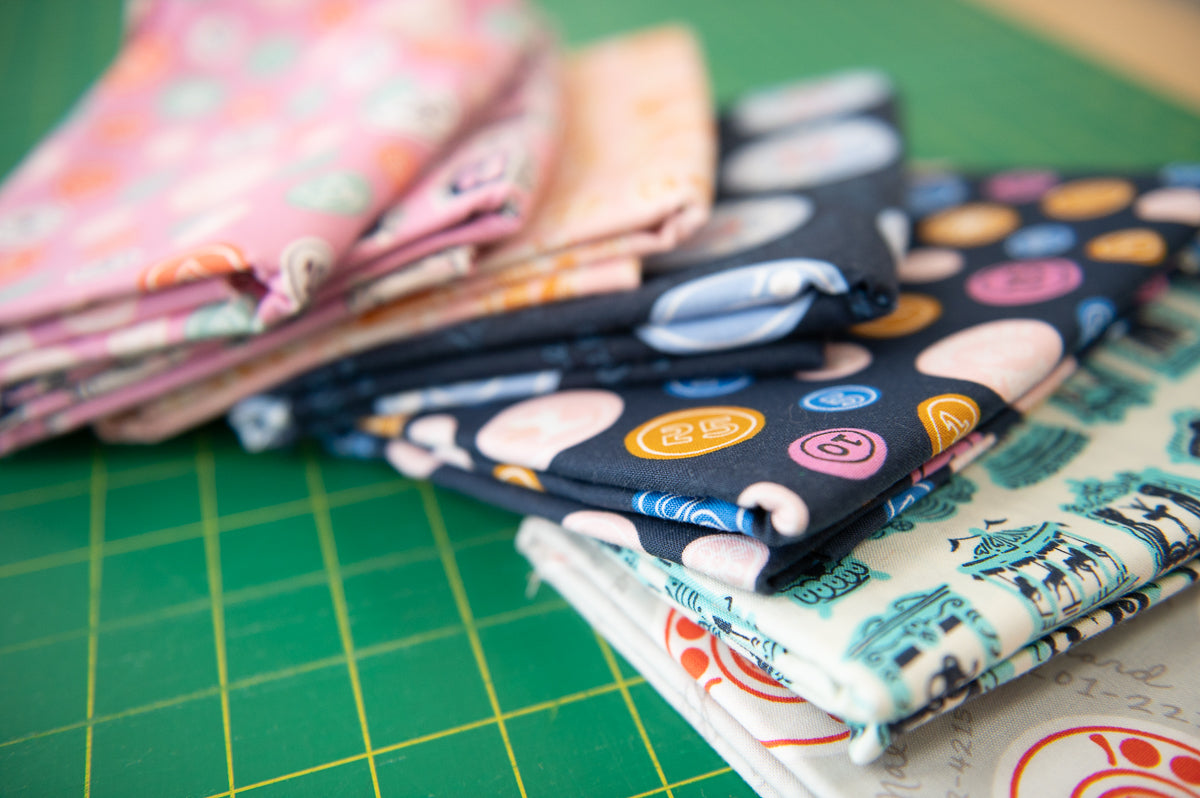 Stack of colorful fabric swatches on a green cutting mat