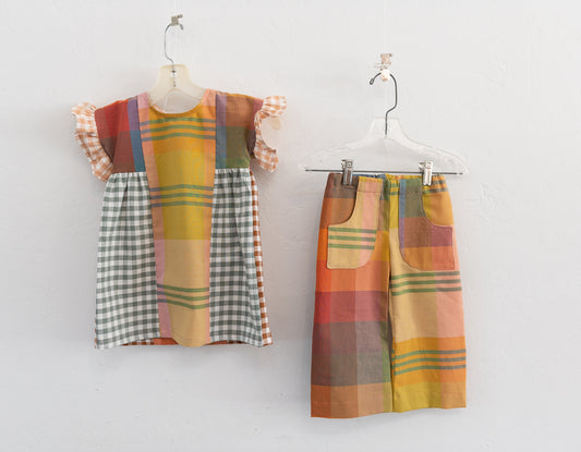 Plaid children's dress and pants on hangers against a white background