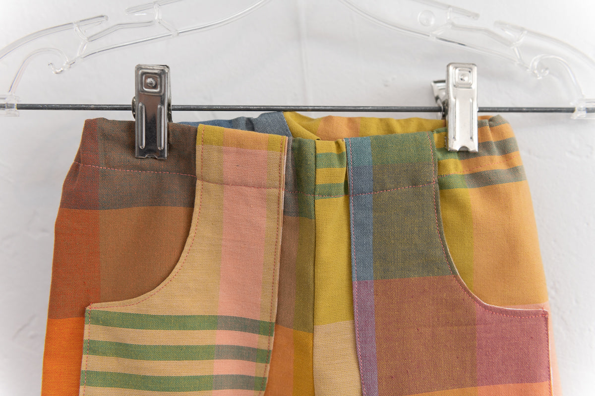 Colorful plaid fabric on a hanger with clips against a white background