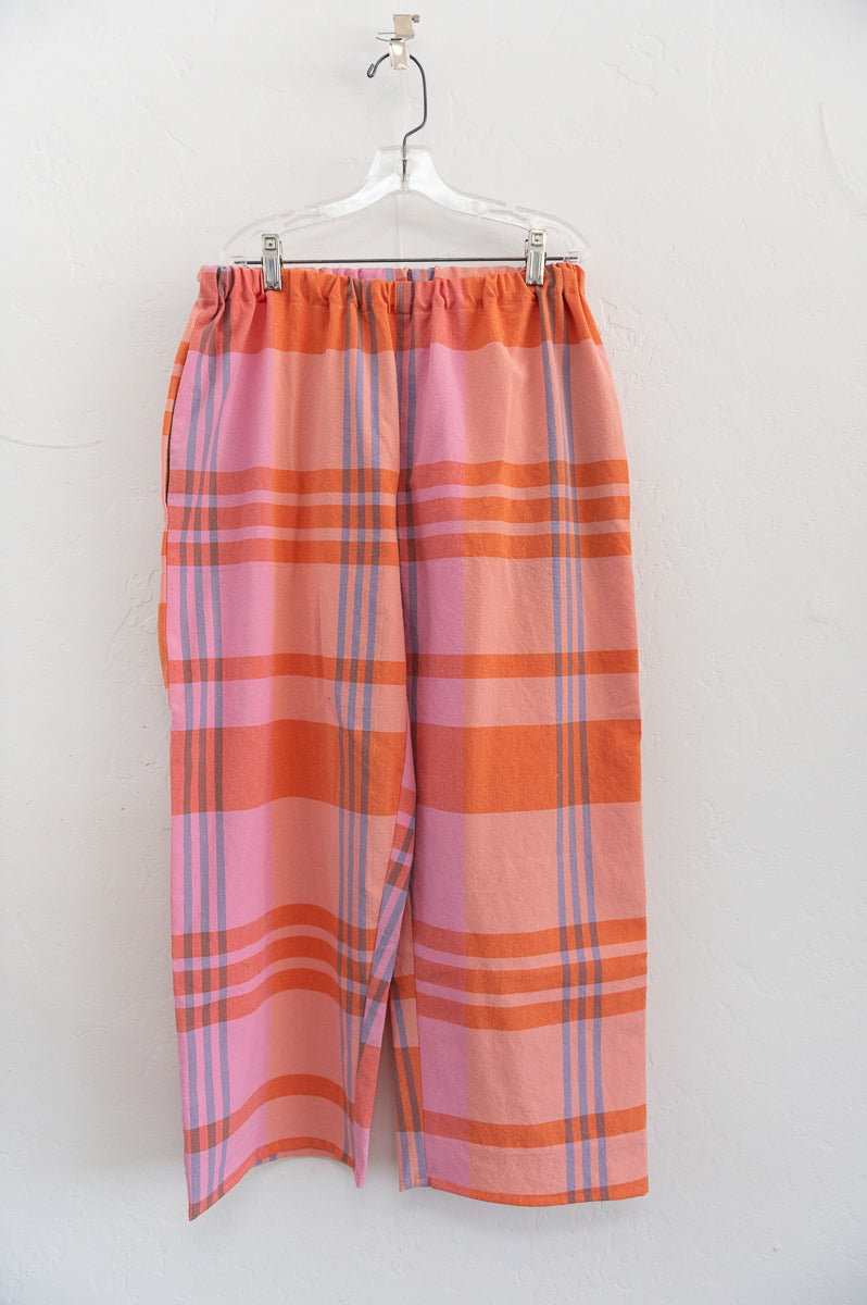 Plaid pants hanging on a white hanger against a white background