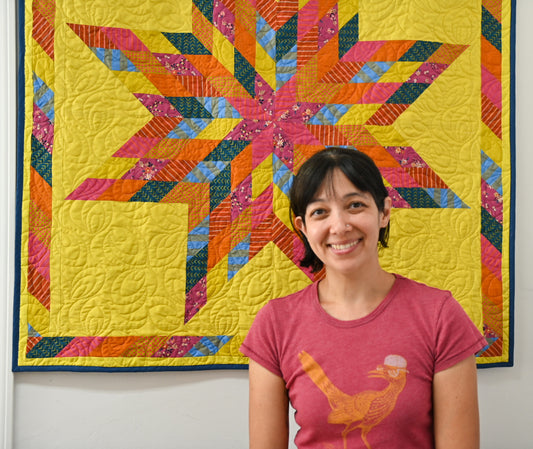 A woman in front of a yellow Lone Star quilt