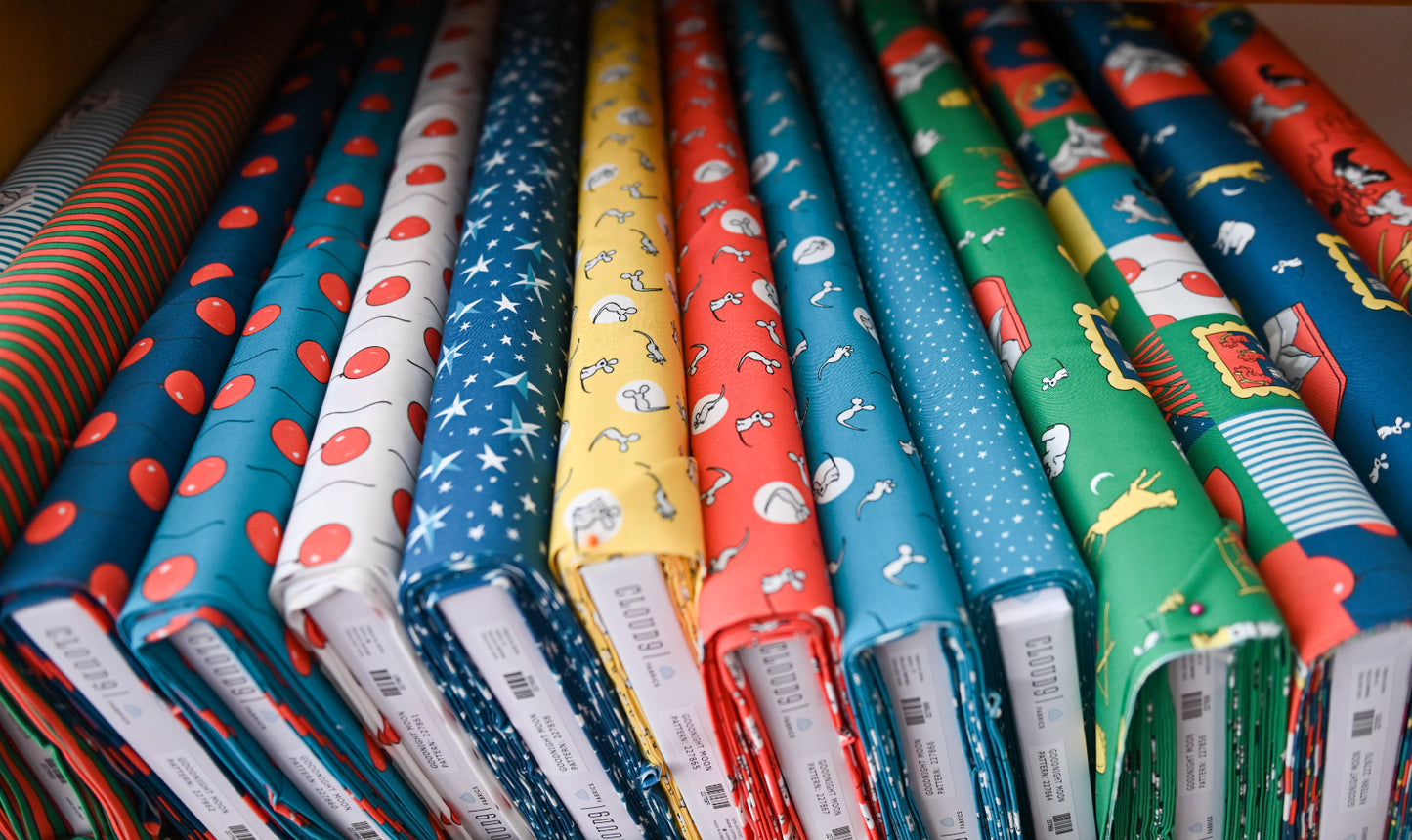 Stack of colorful fabric rolls with various patterns