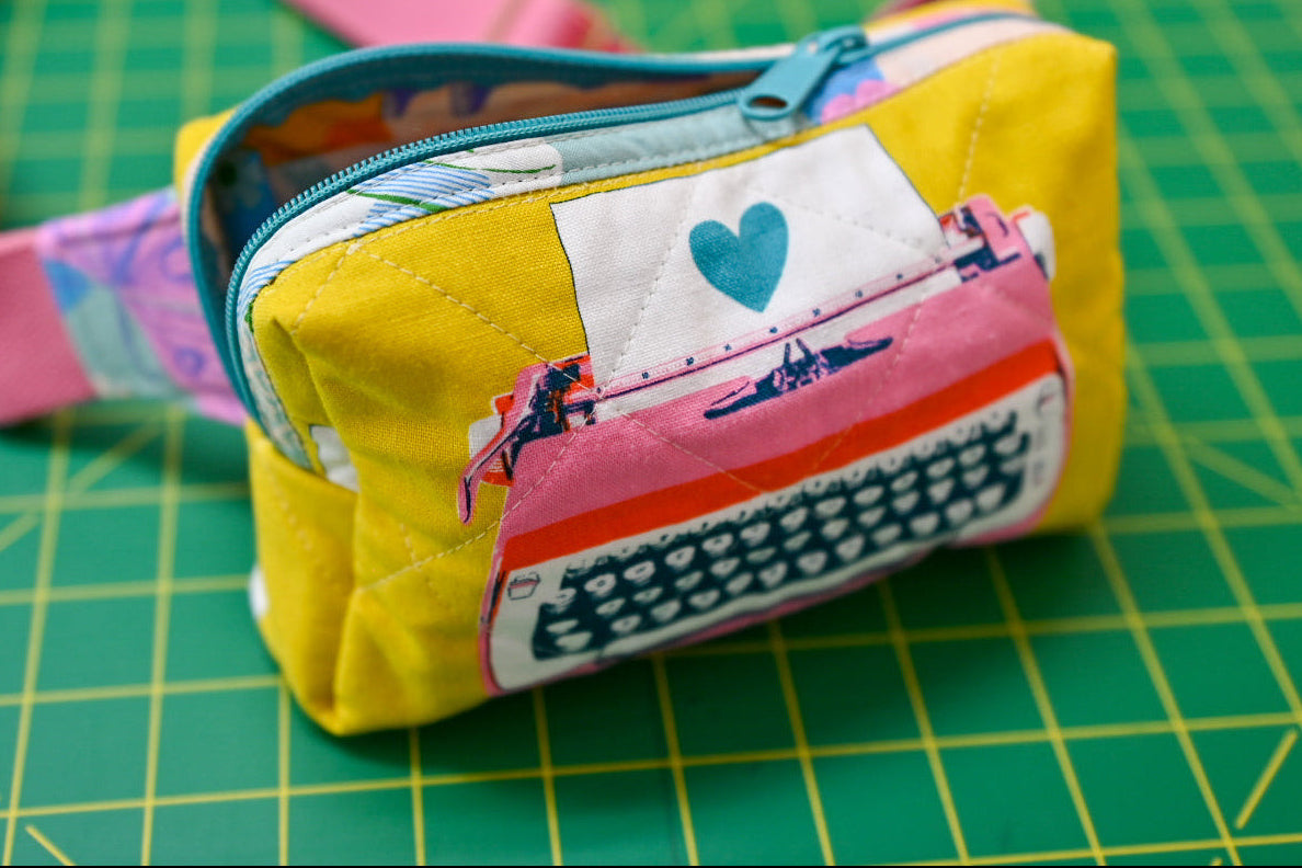 Small fabric pouch with a pink strap on a green cutting mat
