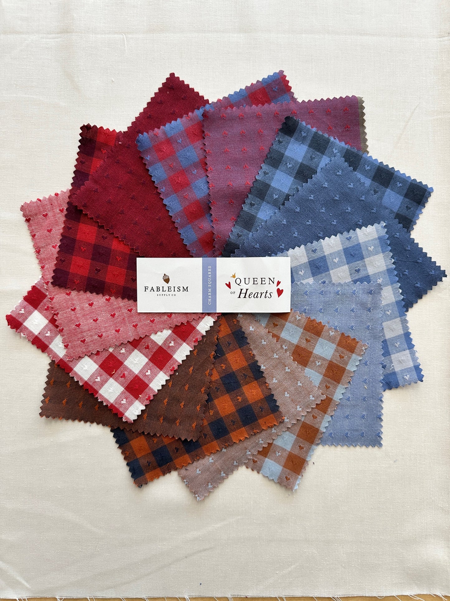 Queen of Hearts Charm Squares featuring a colorful splay of red, mraoon, blue and white and brown fabrics with checkers and tiny hearts