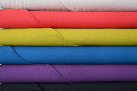 Stack of colorful fabric sheets in red, yellow, blue, and purple.