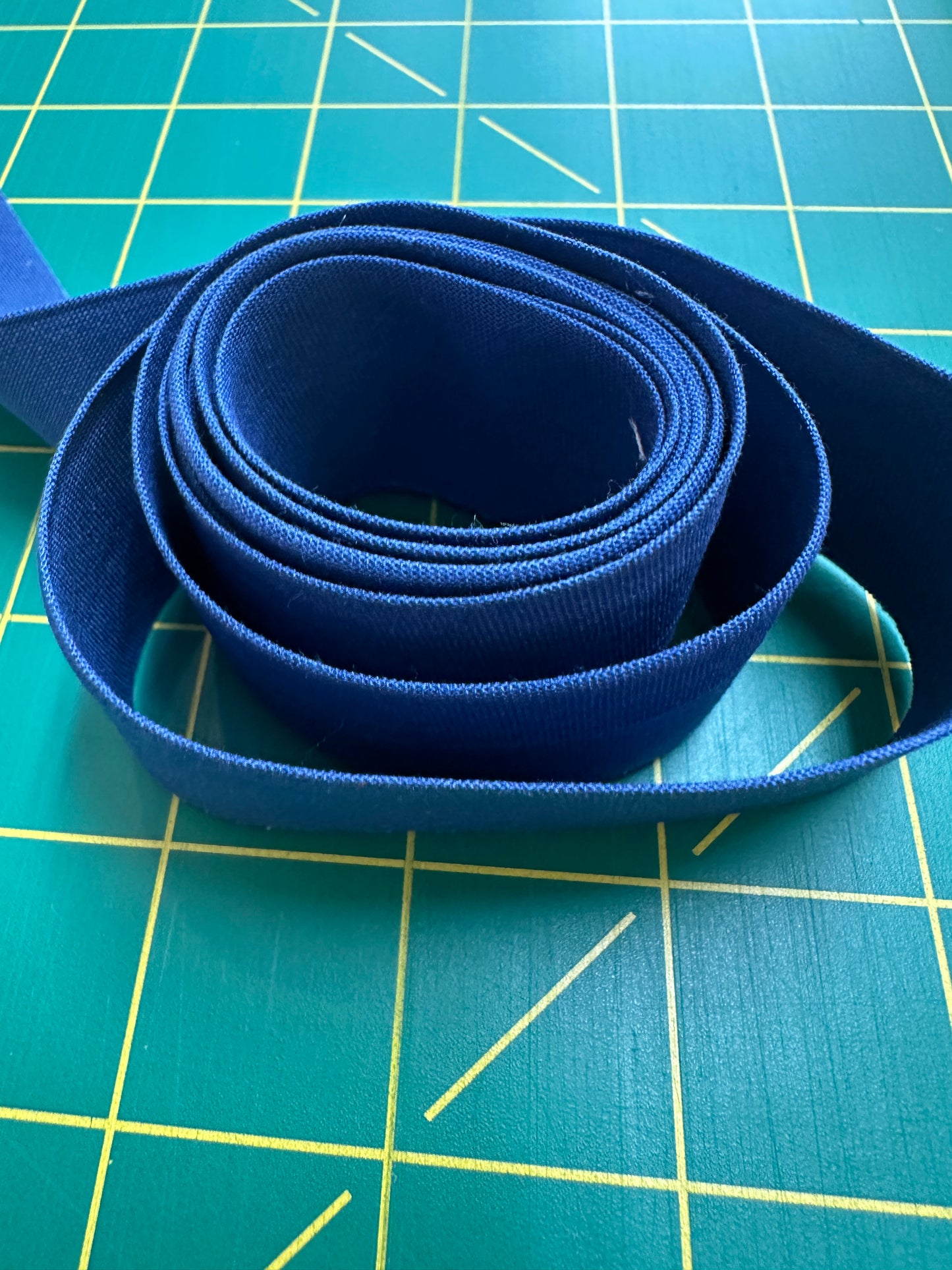 Blue ribbon on a teal cutting mat with yellow grid lines