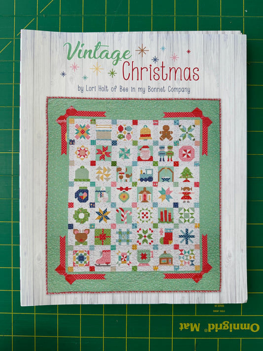 Book titled 'Vintage Christmas' with a colorful quilt design on a green cutting mat.