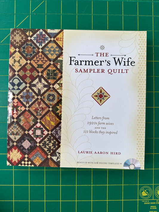 Book titled 'The Farmer's Wife Sampler Quilt' on a green cutting mat