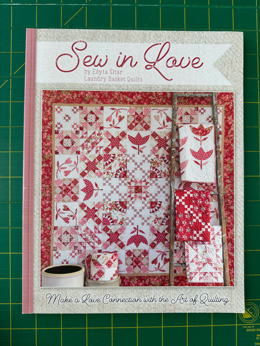 Quilt pattern book titled 'Sew in Love' on a green cutting mat.