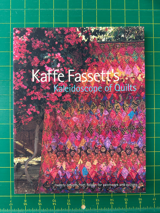 Book titled 'Kaffe Fassett's Kaleidoscope of Quilts' on a green grid background