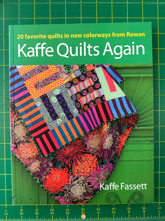 Colorful quilt on a green cutting mat with Kaffe Fassett branding
