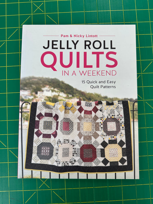 Book titled 'Jelly Roll Quilts in a Weekend' with a quilt on a green cutting mat.