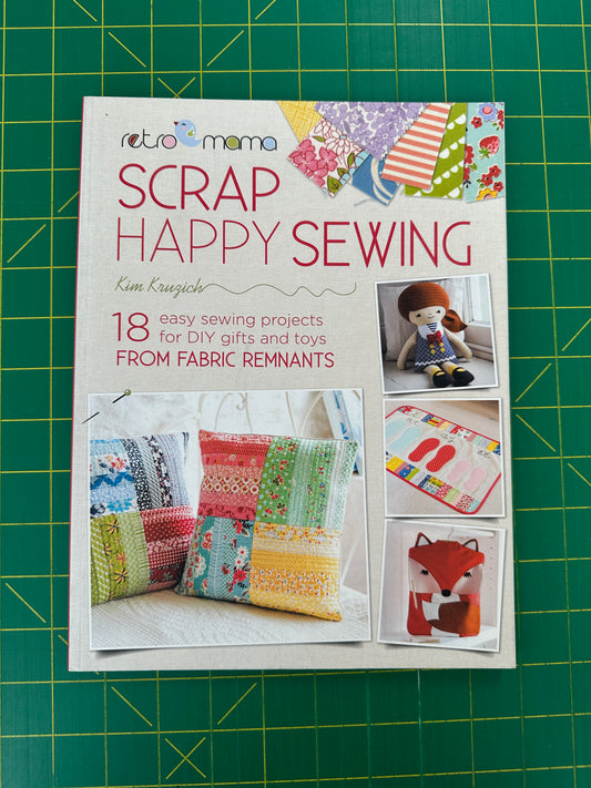 A book titled "Scrap Happy Sewing" on a green cutting mat