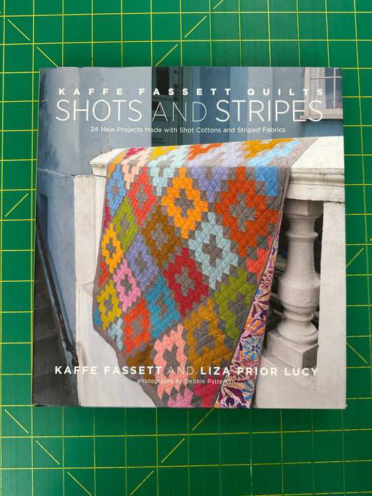 Book titled 'Kaffe Fassett Shots and Stripes' on a green cutting mat