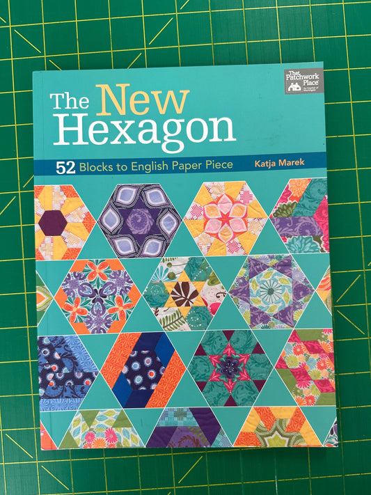 Book titled "The New Hexagon" resting on a green cutting mat