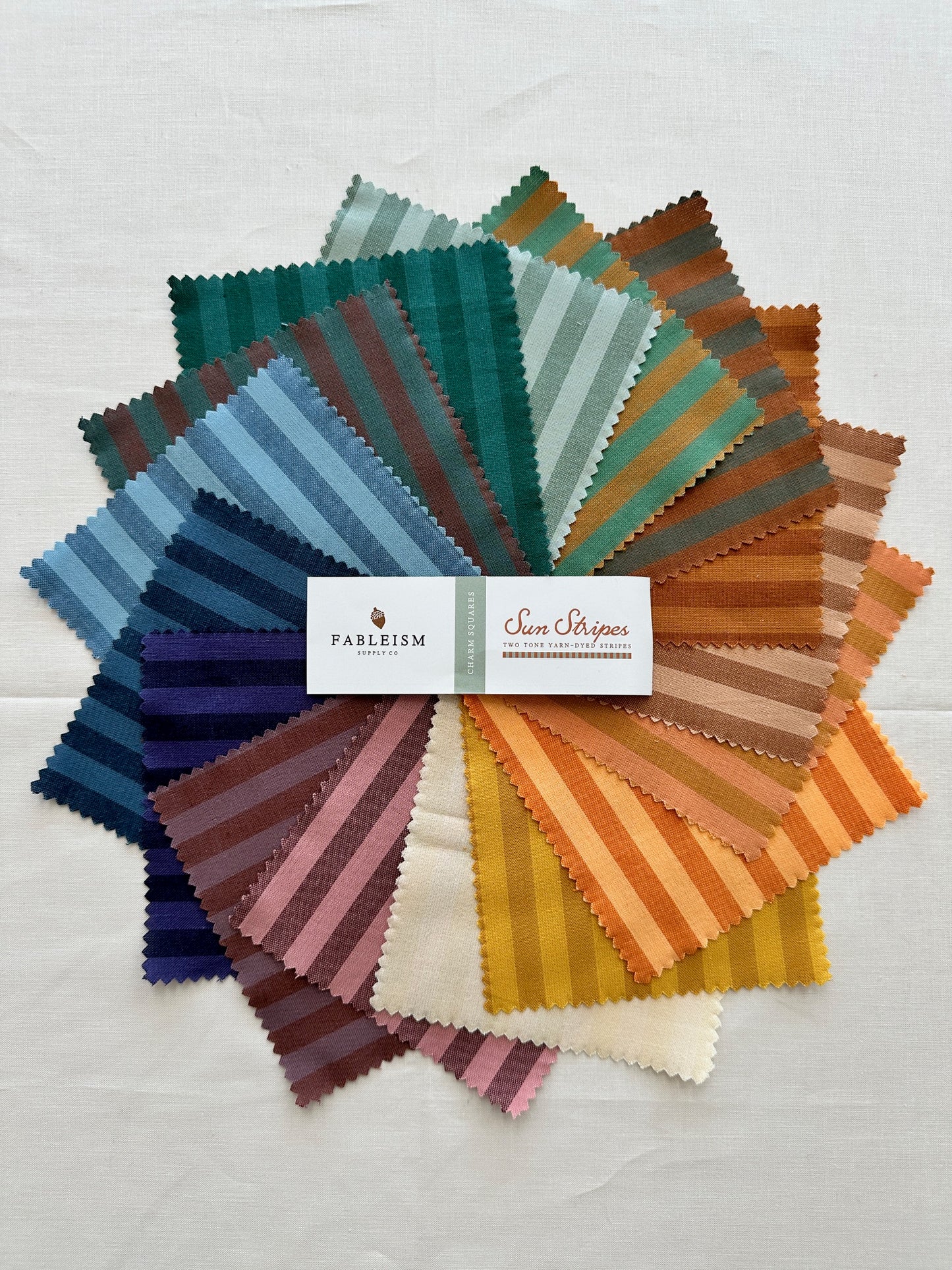Fableism Sun Stripe Fabric arranged in a colorful splay of squares in various striped patterns