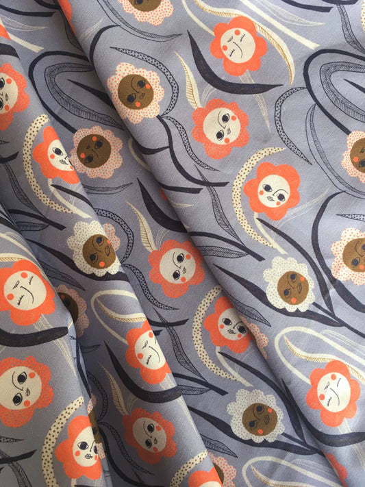 Fabric with a floral pattern featuring orange flowers and brown centers on a gray background