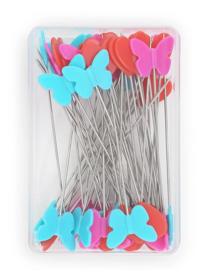 A clear plastic case containing multiple butterfly-shaped pins with long silver metal wires. The butterfly tips are in bright pink, light blue, and coral red, arranged inside a transparent rectangular container on a white background.