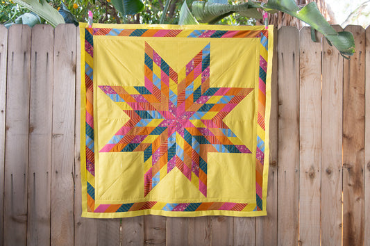 Colorful star-patterned quilt hanging on a wooden fence