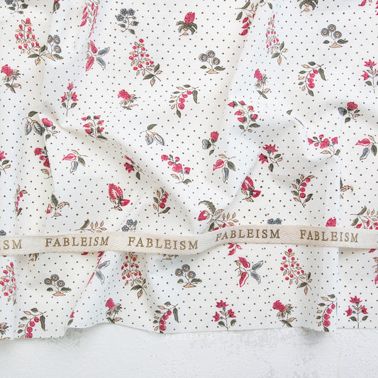 Floral fabric with a ribbon displaying 'Fableism' on a textured surface