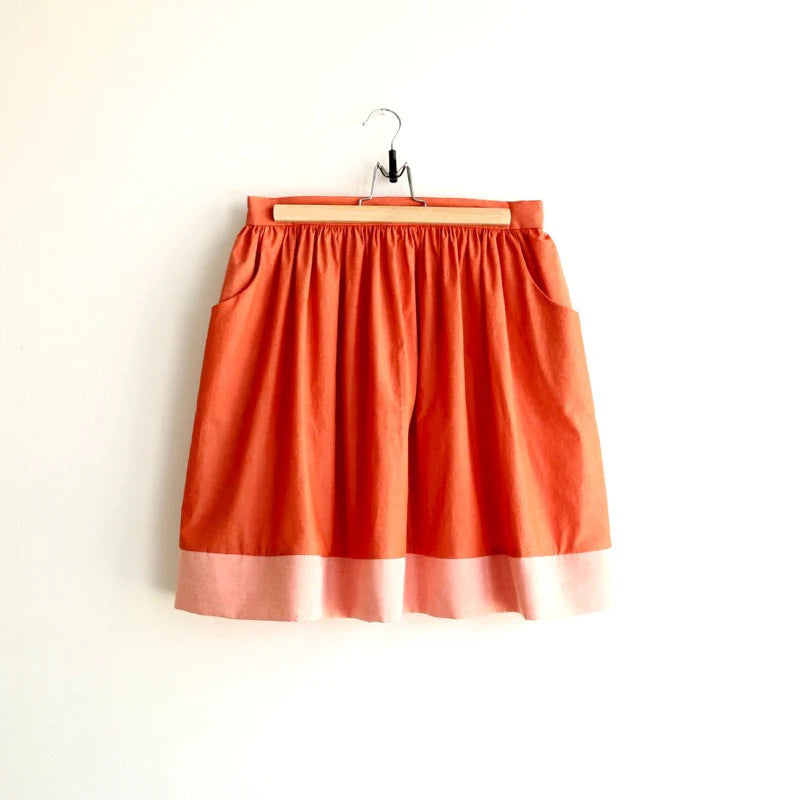 Orange skirt on a hanger against a white background