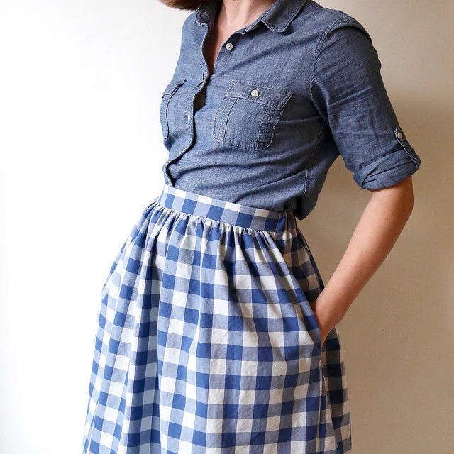 Person wearing a blue checkered dress with a plain background