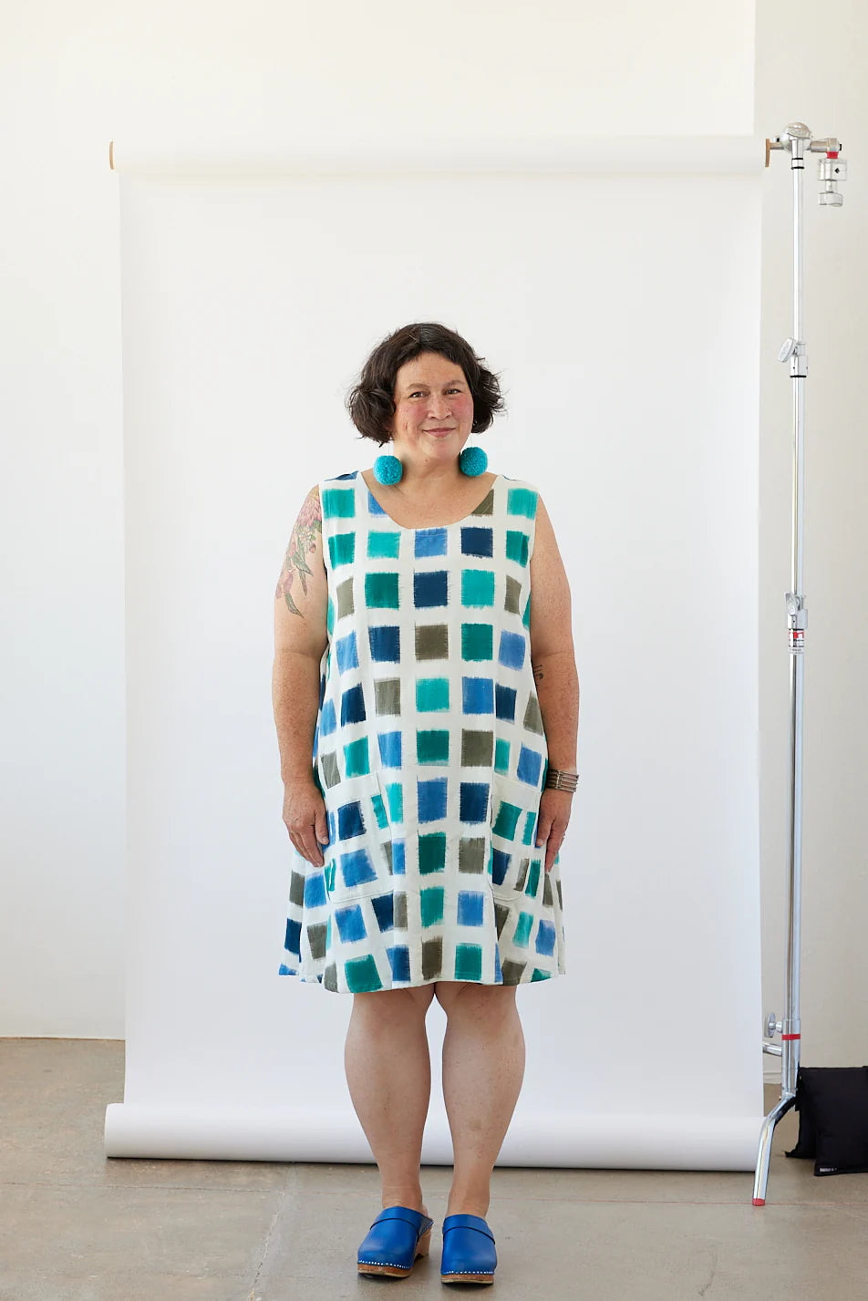 Woman wearing a checkered dress standing in front of a white backdrop