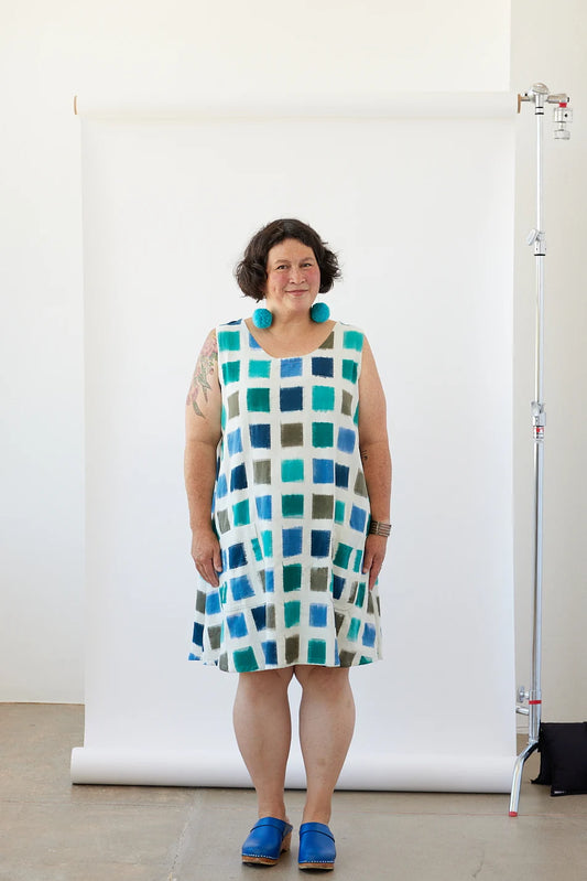 Woman wearing a checkered dress standing in front of a white backdrop