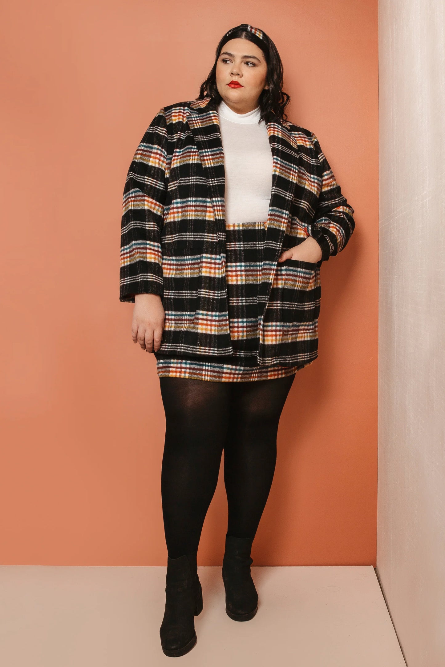 Woman wearing a plaid coat against an orange background