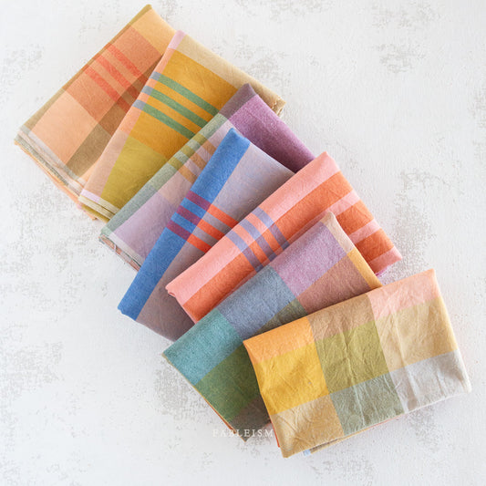 Set of colorful plaid napkins on a textured white surface