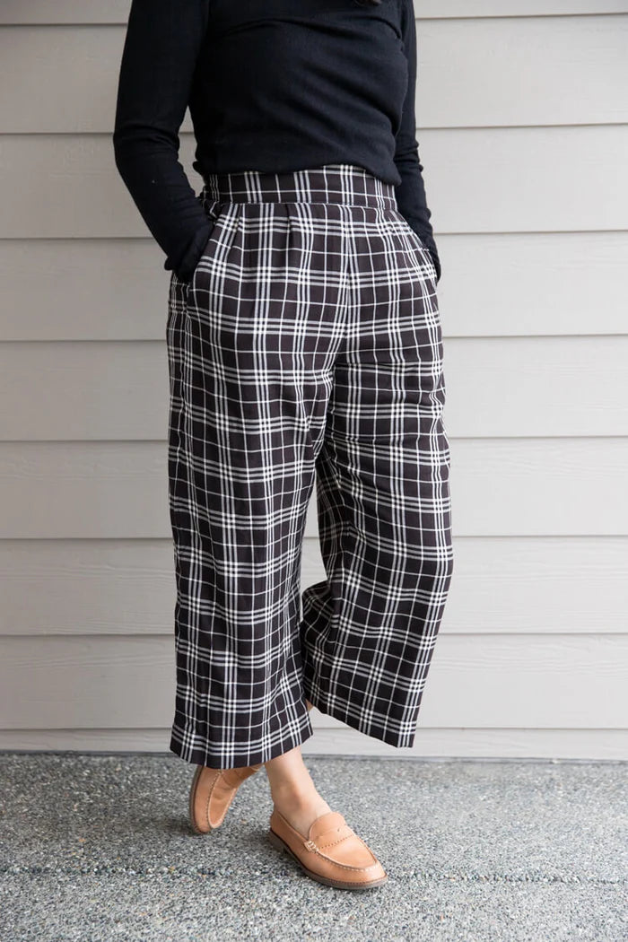 Person wearing black and white plaid pants with a plain background