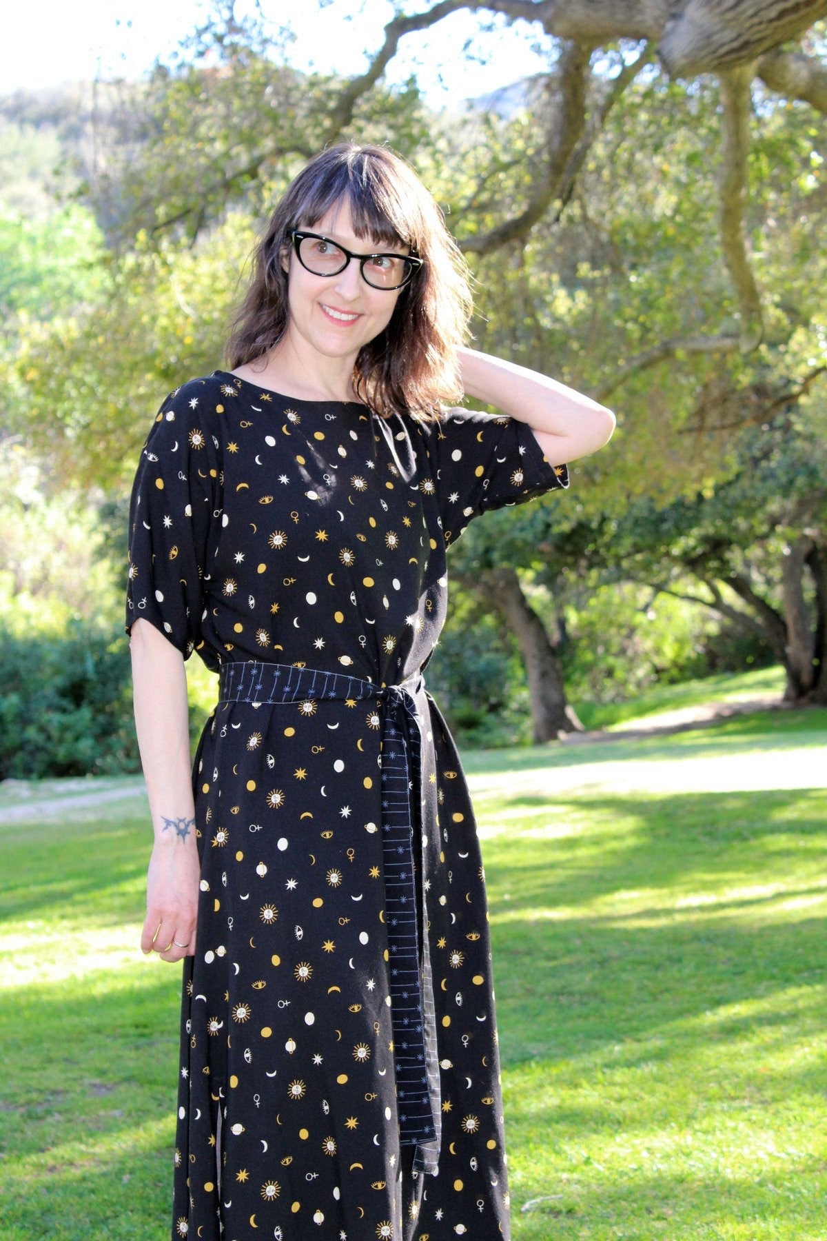 Darcy is wearing a black dress with a fabric tie belt