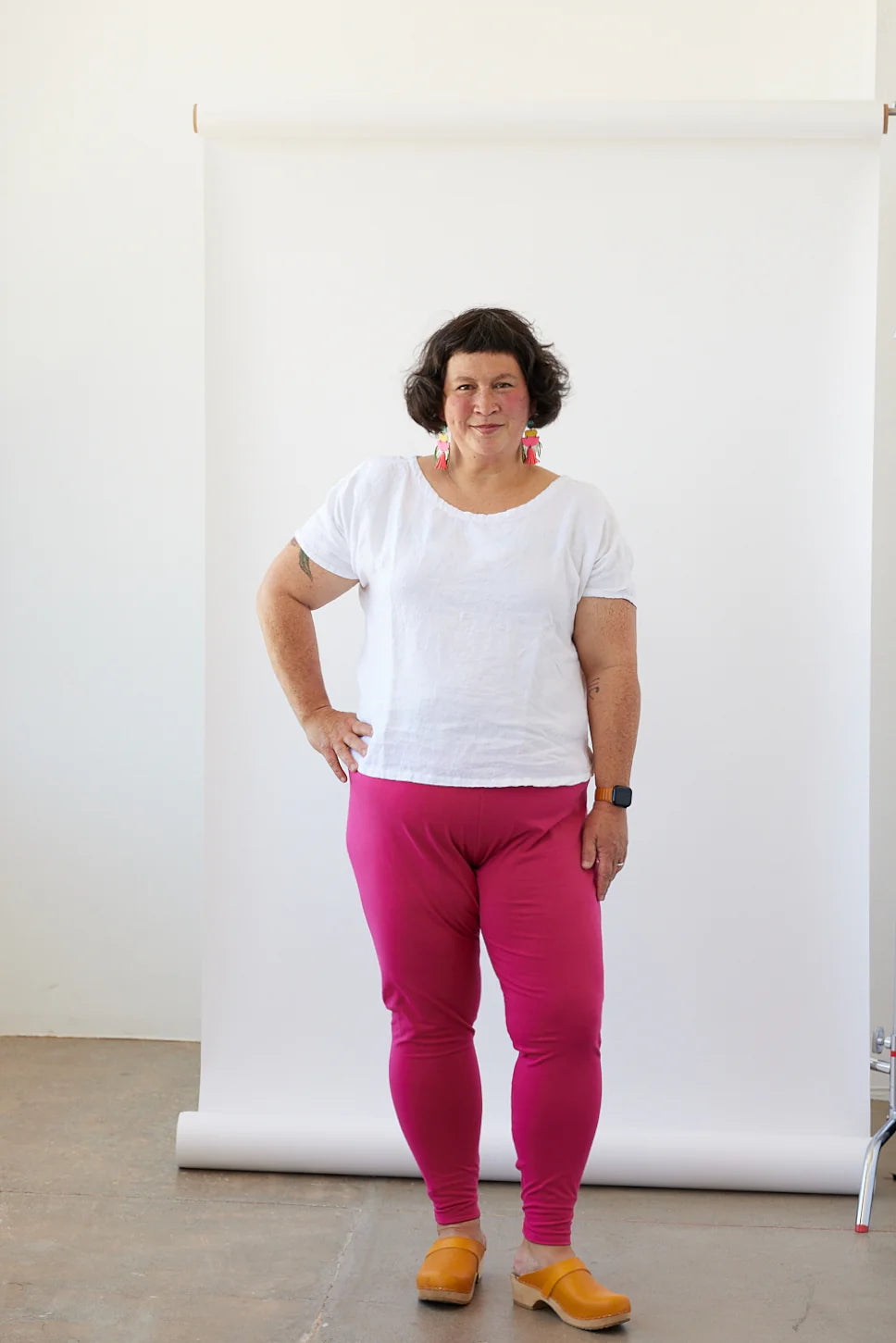 Person wearing a white shirt and pink pants standing against a white backdrop