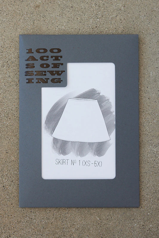 Booklet titled '100 Acts of Sewing' with a diagram of a skirt on a textured surface