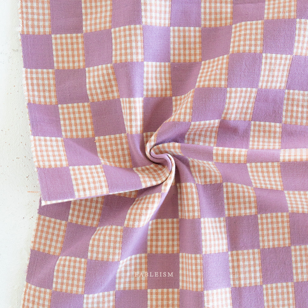 Checkered fabric with purple and peach pattern on a white background