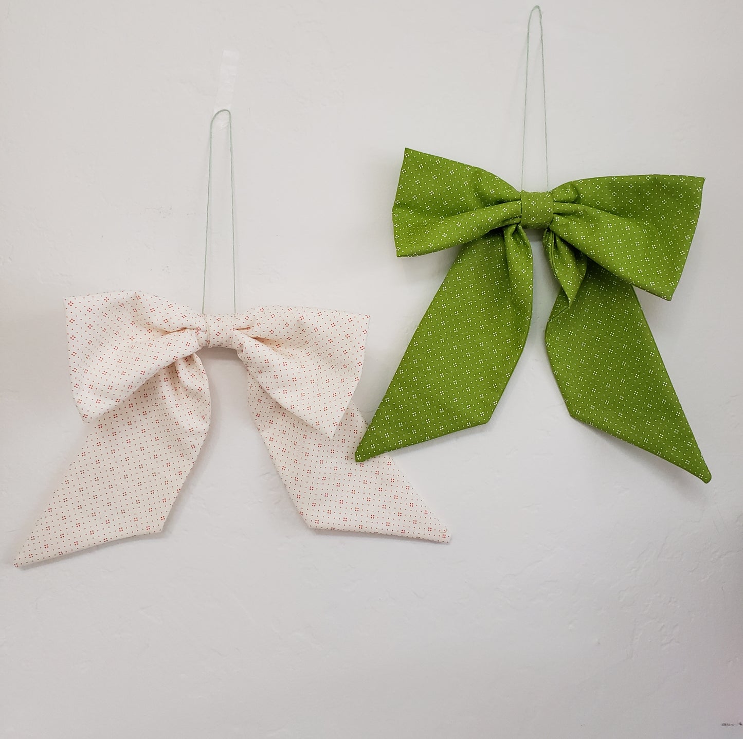 Two fabric bows, one green and one beige, on a plain background