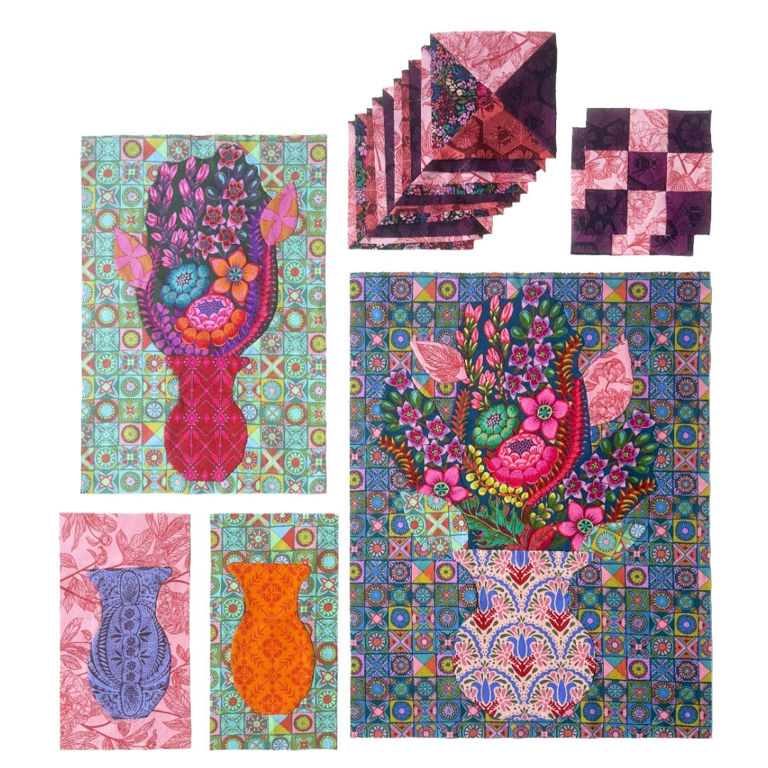 A set of colorful quilted fabric pieces featuring floral and vase motifs on a white background, including a large central quilt, a stack of folded matching quilts, and two smaller square quilts.