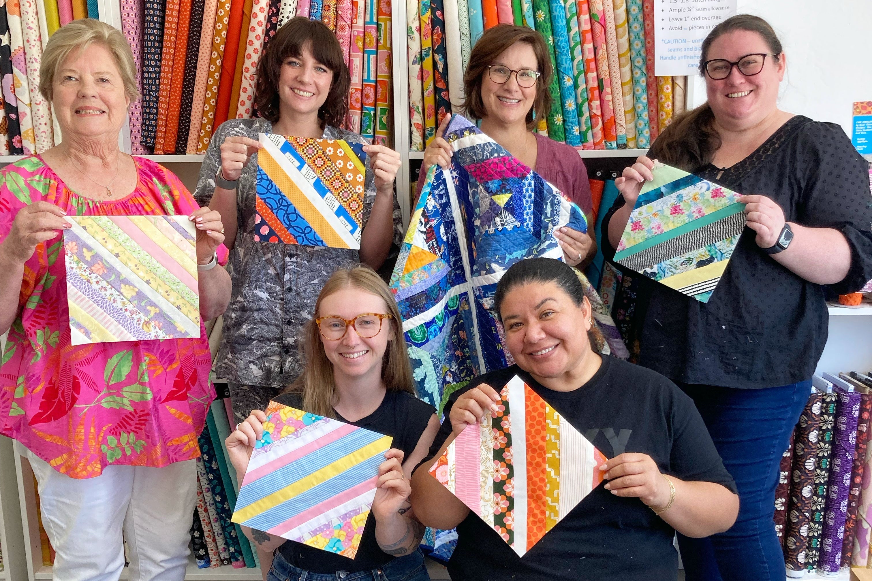 Group of people holding colorful fabric triangles in a craft store.