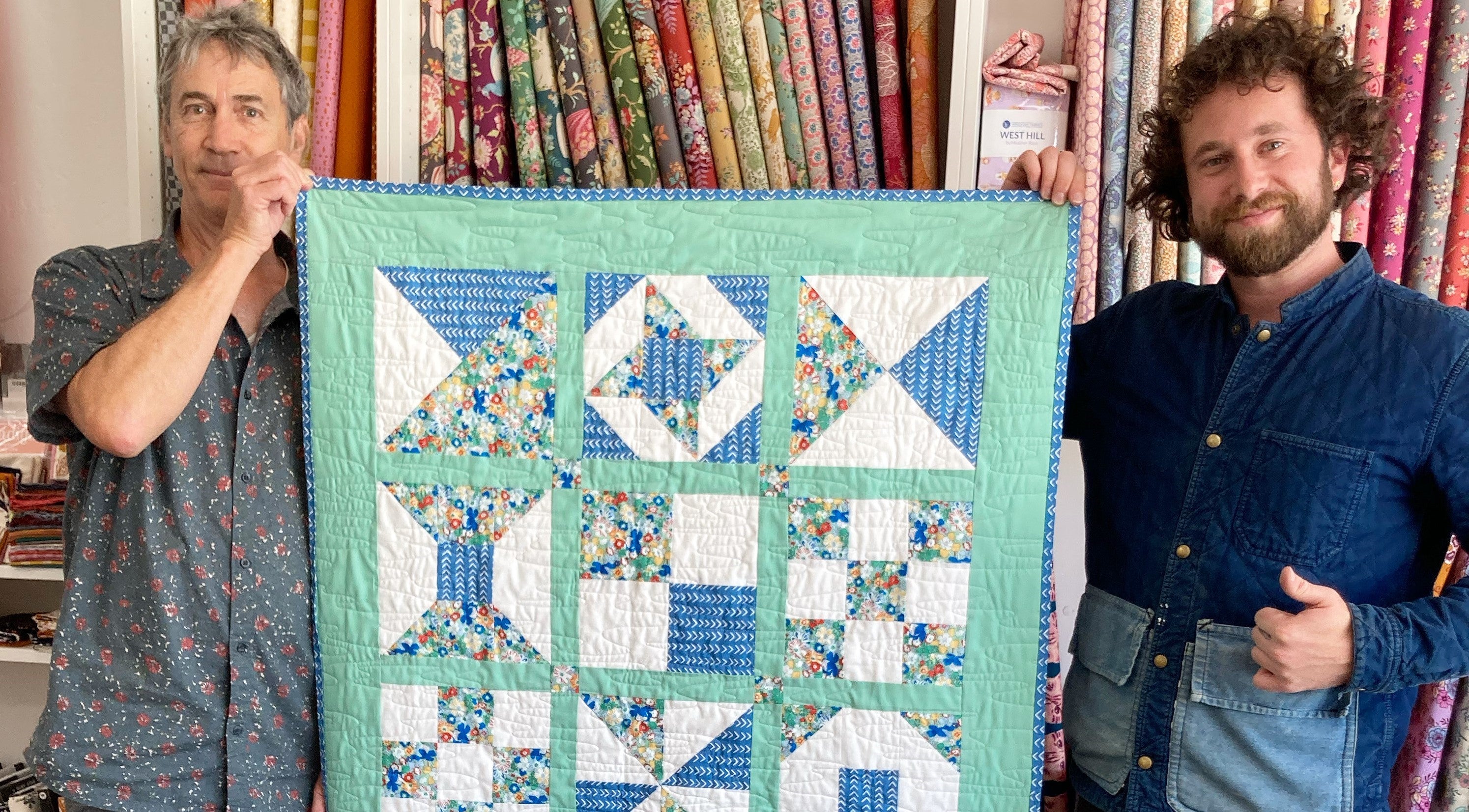Two people holding up a quilt made at QuiltnThings studio