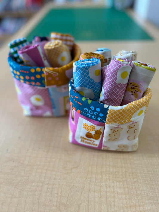 Colorful fabric rolls in a basket on a wooden surface