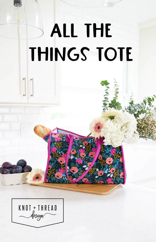 Floral tote bag with flowers and bread on a white surface, with text 'All the Things Tote' and brand name 'Knot + Thread Design'.