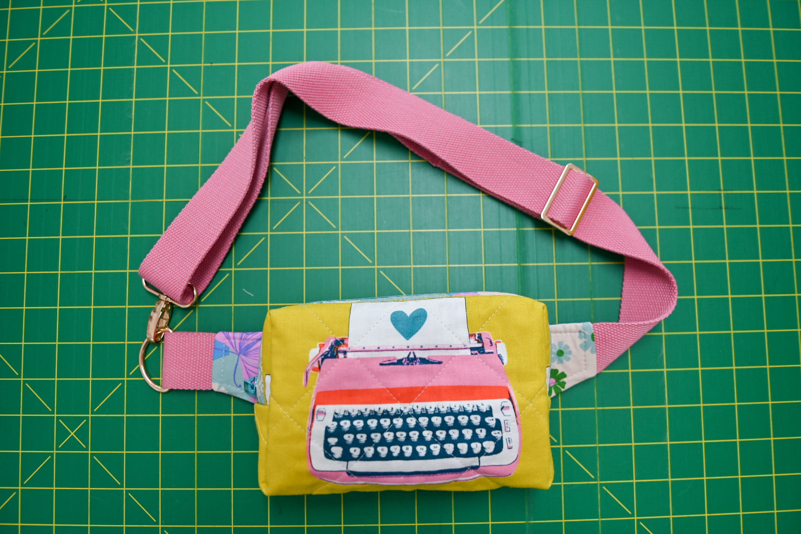 Fanny pack with pink strap on a green cutting mat