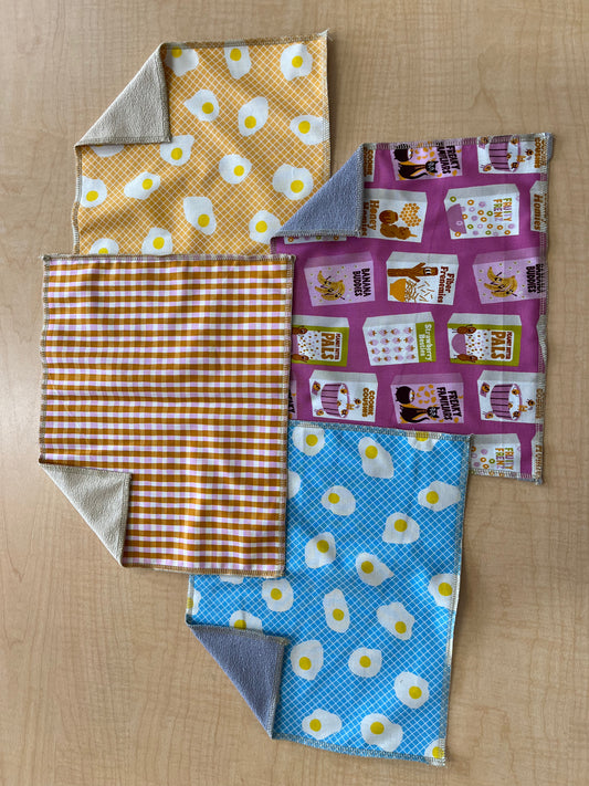 Four fabric swatches with different patterns on a wooden surface
